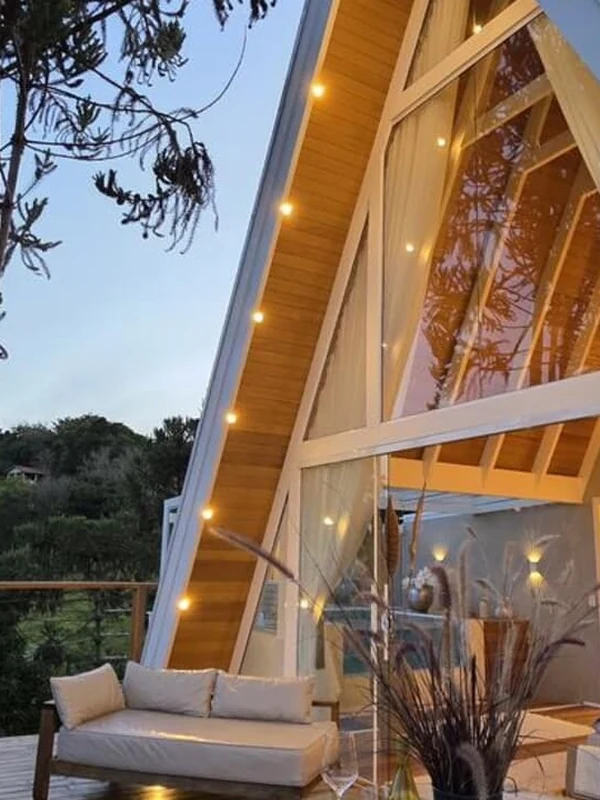 A Cabana Blanc, A-frame branca iluminada ao entardecer, com vista das montanhas
